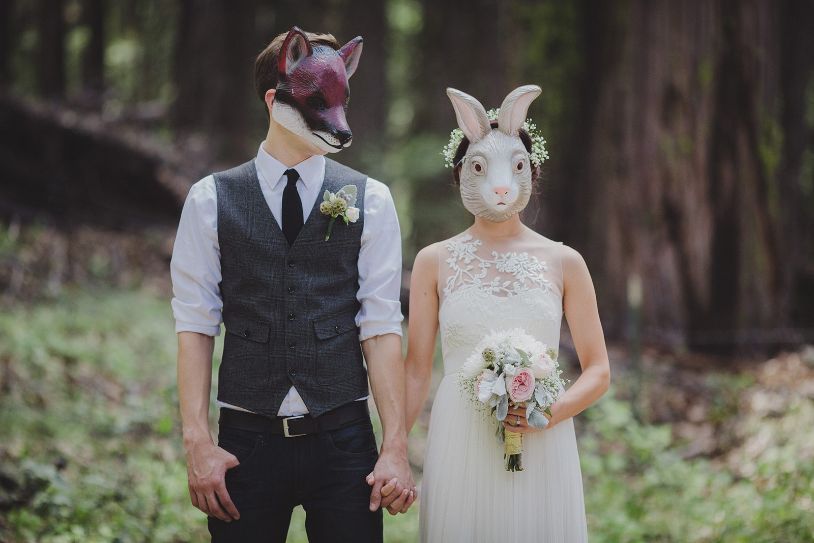 A man and woman wearing masks holding hands.