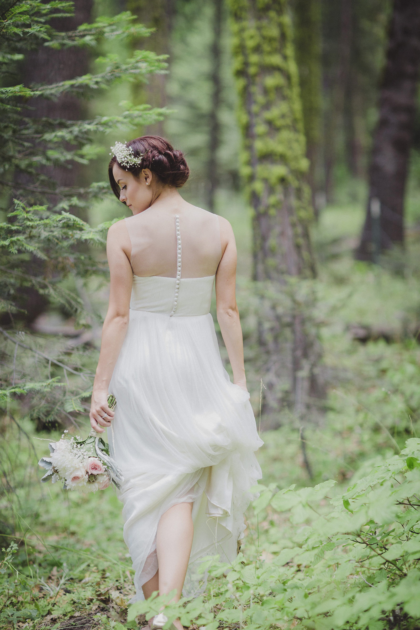 A bride in the woods holding her bouquet