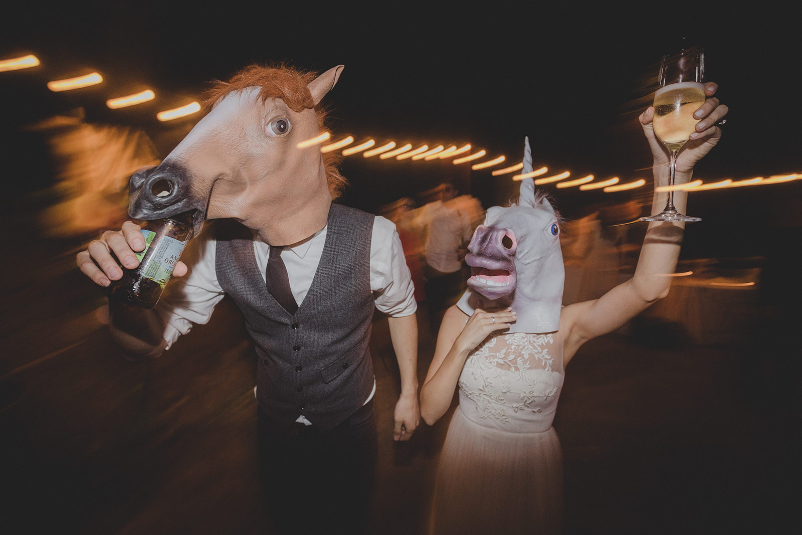 A man and woman wearing horse masks at night.