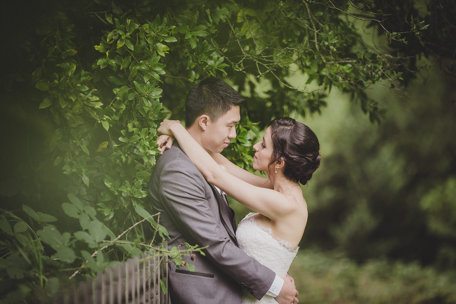 A man and woman embracing in front of trees.