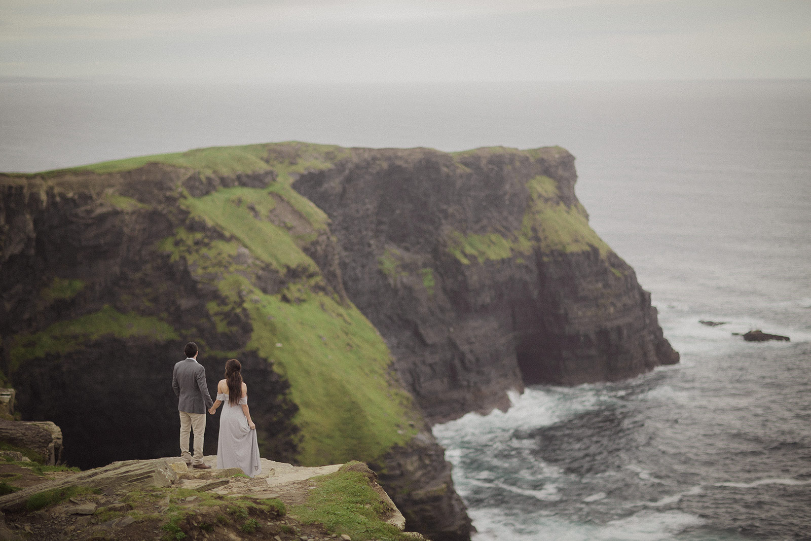 A couple standing on the side of a cliff.