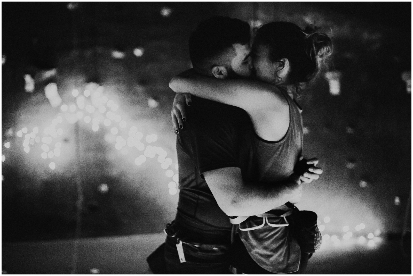 A man and woman hugging in front of lights.
